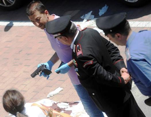Un perito tiene in mano la pistola usata per la sparatoria che ha causato 4 feriti gravi a Ponte Valleceppi, alla periferia di Perugia, 6 luglio 2014.