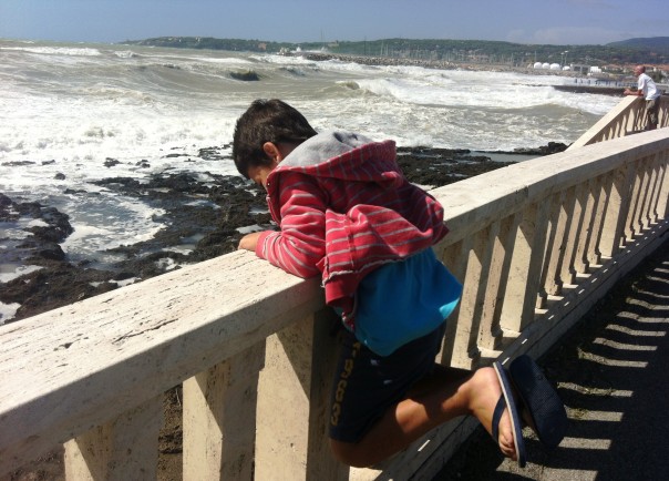 Un bimbo gioca davanti alla mareggiata a Rosignano Solvay