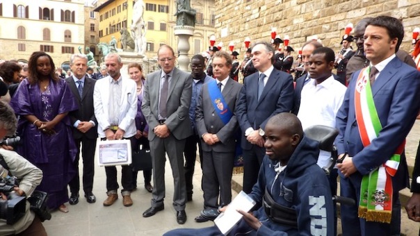 Moustapha Dieng (sulla sedia a rotelle) con il sindaco di Firenze Matteo Renzi il giorno del conferimento della cittadinanza italiana. Era il 2 giugno 2013