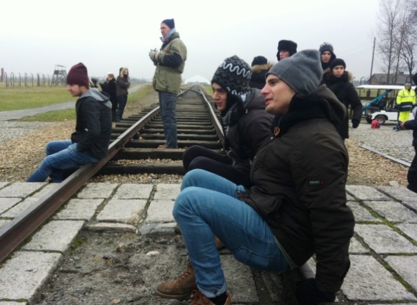 Birkenau, ragazzi in pausa nella visita, seduti sul binario dei treni dei deportati