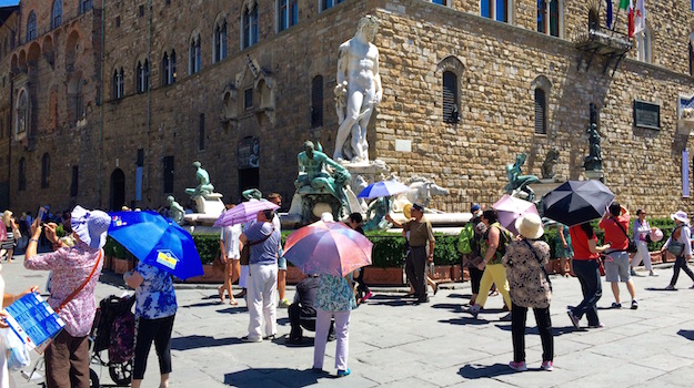 Turisti con l'ombrello oggi in piazza Signoria a Firenze alle 14