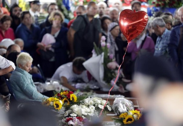 A balloon shaped like a heart and reading in Italian "Goodbye Anna" floats over caskets prior to a state funeral for some of the victims of last Wednesday's earthquake, in Amatrice, central Italy, Tuesday, Aug. 30, 2016. The service will take place on the edge of Amatrice's obliterated medieval town center on the grounds of a Catholic retreat. It comes as Italy observed a second day of national mourning, with flags on public buildings flying at half-staff. (ANSA/AP Photo/Andrew Medichini) [CopyrightNotice: Copyright 2016 The Associated Press. All rights reserved.]