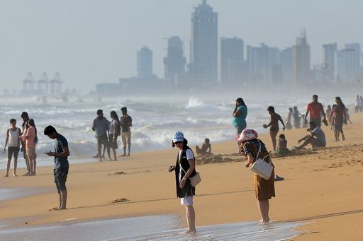 In this photograph taken on July 3, 2016, foreign tourists walk along Mount Lavinia beach on the outskirts of Colombo. Tourists have flocked back to Sri Lanka's shores since a bloody civil war ended in 2009, but environmentalists say the island is a victim of its own success as sewage from its thriving hotels pollutes its once pristine beaches. / AFP PHOTO / LAKRUWAN WANNIARACHCHI / TO GO WITH AFP STORY SRI LANKA-TOURISM-POLLUTION,FEATURE BY AMAL JAYASINGHE