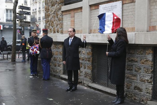 French President Francois Hollande and Paris Mayor Anne Hidalgo unveil a commemorative plaque next to the "La Belle Equipe" bar and restaurant in Paris, France, Sunday, Nov. 13, 2016, during a ceremony held for the victims of last year's Paris attacks which targeted the Bataclan concert hall as well as a series of bars and killed 130 people. (Philippe Wojazer/Pool Photo via AP)