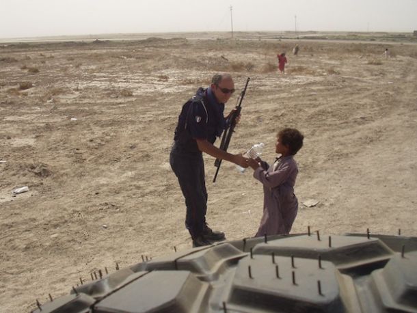 Un carabiniere lascia una bottiglia d'acqua ad un bimbo