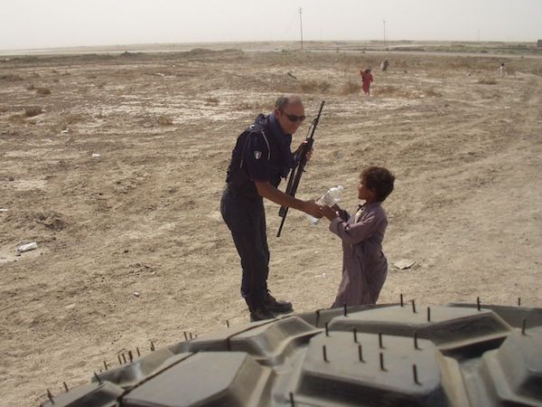 Un carabiniere lascia una bottiglia d'acqua ad un bimbo