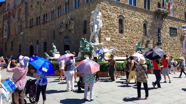 Turisti con l'ombrello oggi in piazza Signoria a Firenze alle 14